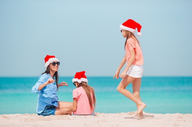 Family of mother and kids in santa hat on the beach vacation at Christmas