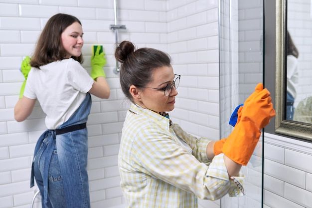 Foto madre di famiglia e figlia adolescente che puliscono insieme a casa in bagno. bambino che aiuta i genitori, le pulizie, lo stile di vita, i lavori domestici