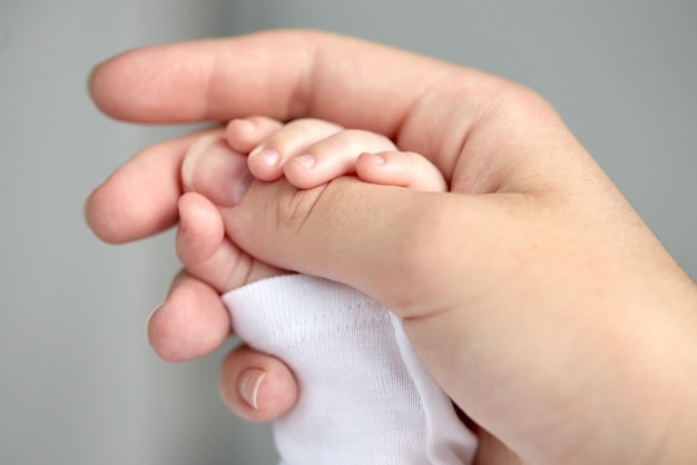 family, motherhood, parenting, people and child care concept - close up of mother and newborn baby hands