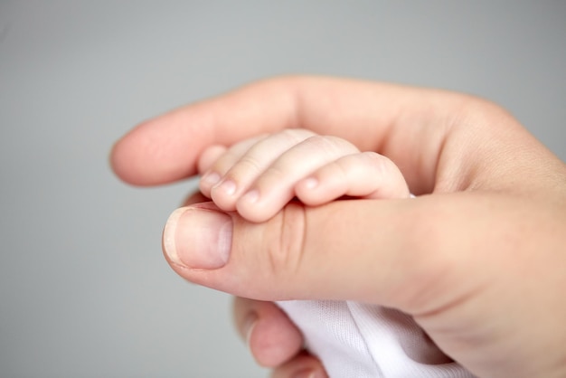 family, motherhood, parenting, people and child care concept - close up of mother and newborn baby hands