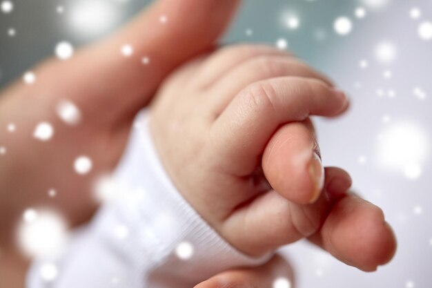 Family motherhood people and child care concept close up of mother and newborn baby hands over snow