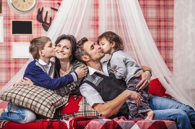 Family mum dad and kids together at home in the cosy atmosphere of the bedrooms in winter interior