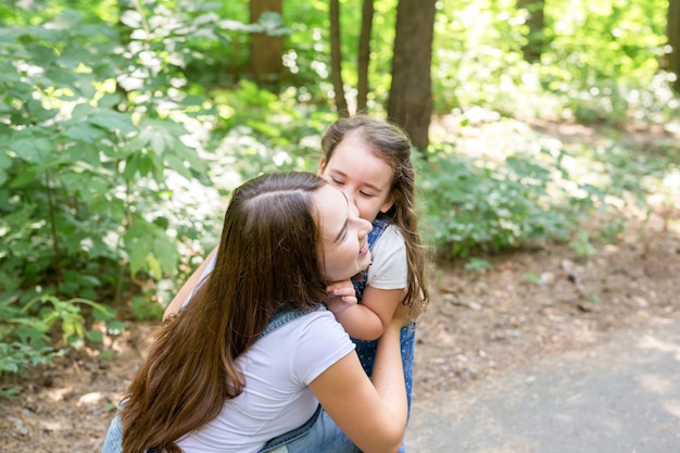 家族と自然の概念-魅力的な若い女性は公園で彼女の小さな娘と一緒に楽しんでいます