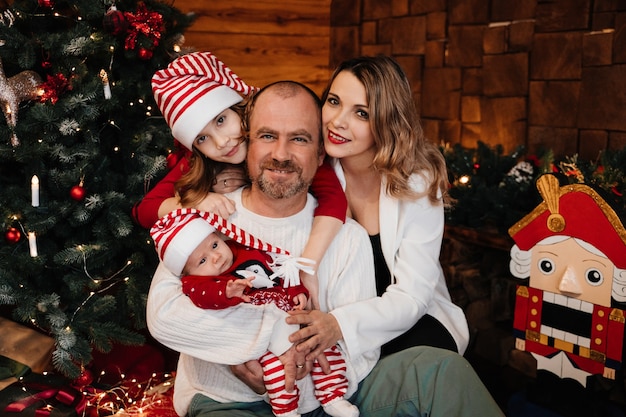 Family near the Christmas tree, children in Christmas costumes