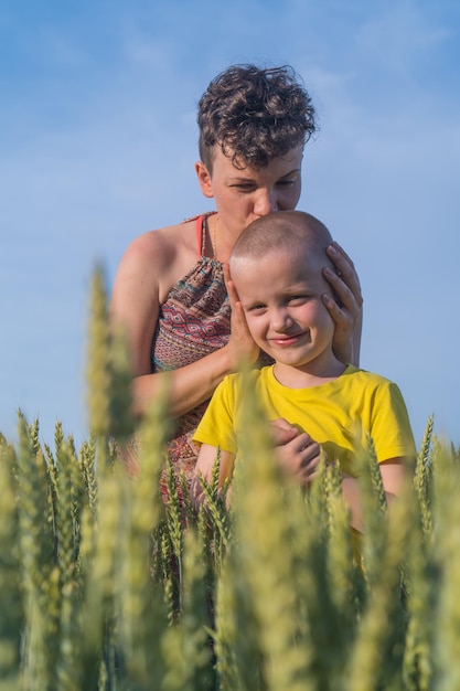 Family outdoor activities mother and son look at spikelets of wheat mother kisses son in the head in...