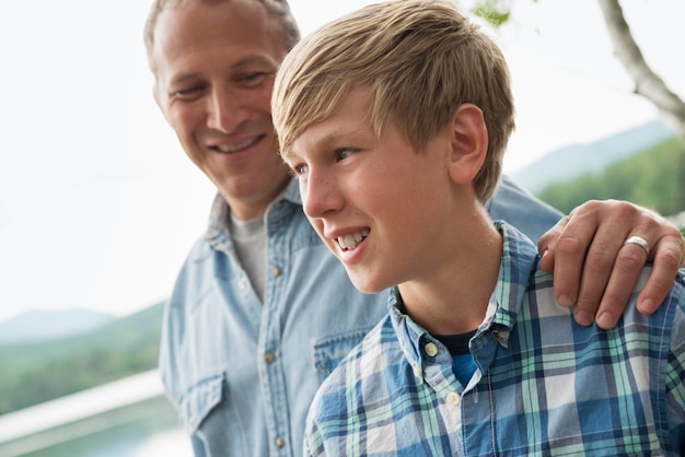 A family outdoors under the trees on a lake shore Father and son