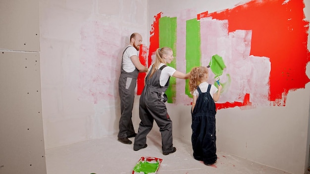 Family painting walls in the new apartment in green and red\
colors