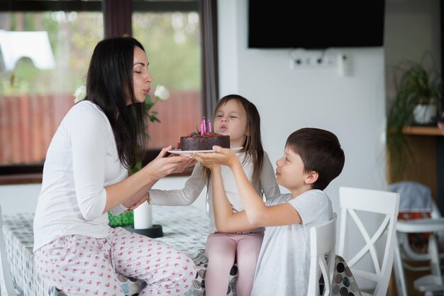 Family in pajamas congratulates mom on her birthday and gives her a cake