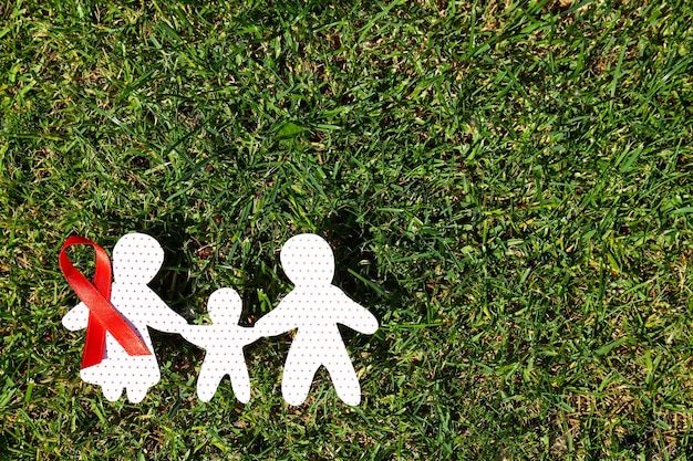 Family paper shapes and awareness ribbon on grass space for text