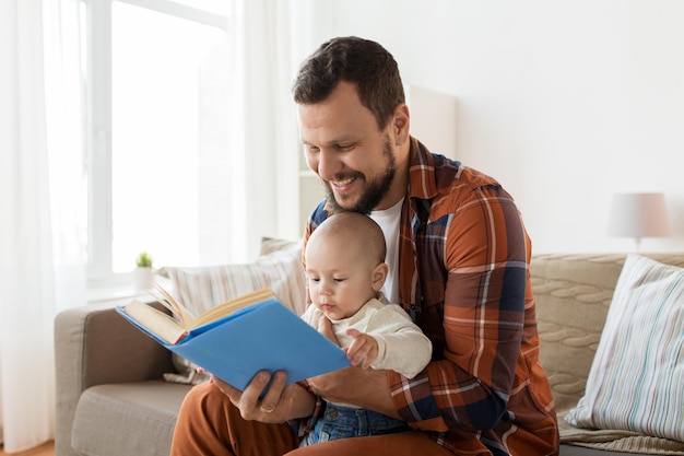 家で本を持った幸せな父親と小さな赤ちゃんの男の子