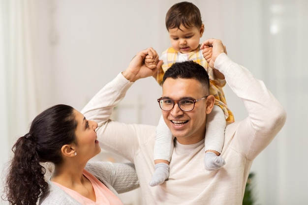 family parenthood and people concept happy mother father and baby daughter playing at home