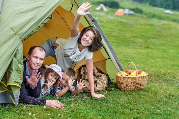 Семья Родители и двое детей в походной палатке Счастливая мать, отец, сын и дочь на летних каникулах