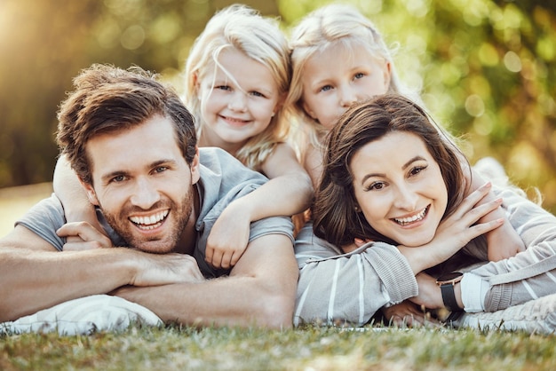 Фото Семейный парк и открытый портрет родителей и девочек с любовью и заботой на природе мама-папа и дети с улыбкой летом чувствуют себя счастливыми на зеленой траве, сближаясь на пикнике