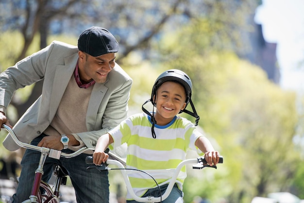 晴れた日に公園にいる家族自転車に乗って楽しんでいる父と息子が並んでいる