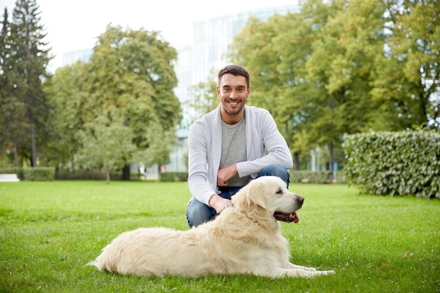 家族、ペット、動物、人のコンセプト – ラブラドル・レトリーバー犬が都市公園を歩く幸せな男性