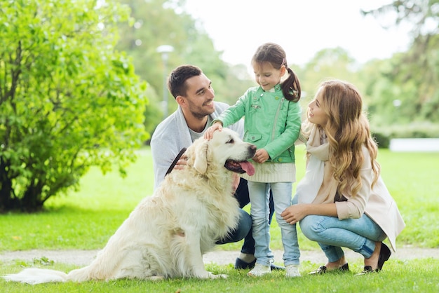 family, pet, domestic animal and people concept - happy family with labrador retriever dog on walk in summer park