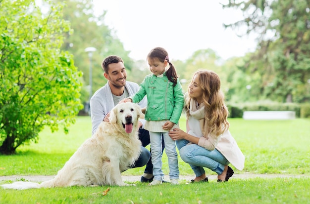 family, pet, domestic animal and people concept - happy family with labrador retriever dog on walk in summer park