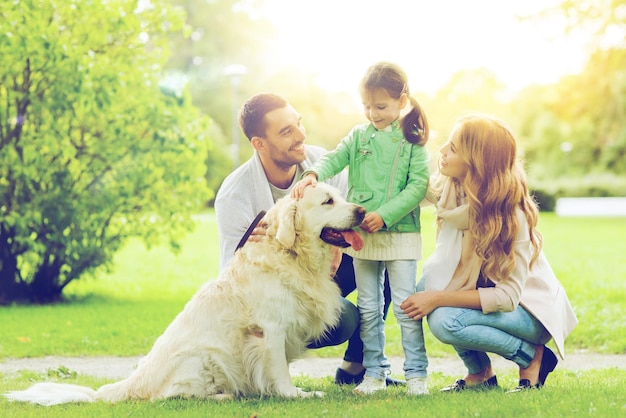 family, pet, domestic animal and people concept - happy family with labrador retriever dog on walk in summer park