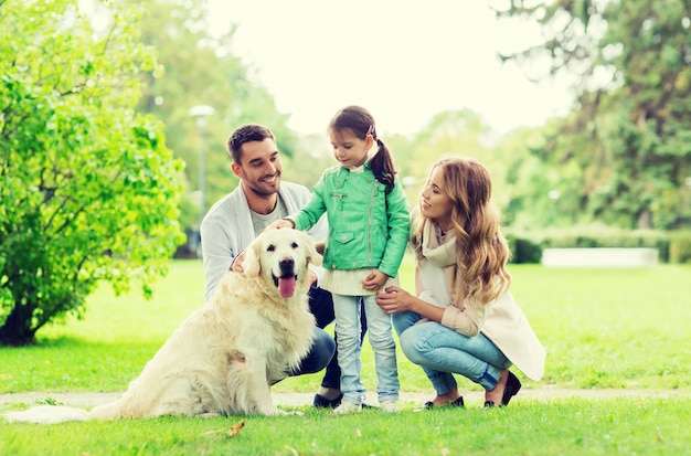 family, pet, domestic animal and people concept - happy family with labrador retriever dog on walk in summer park