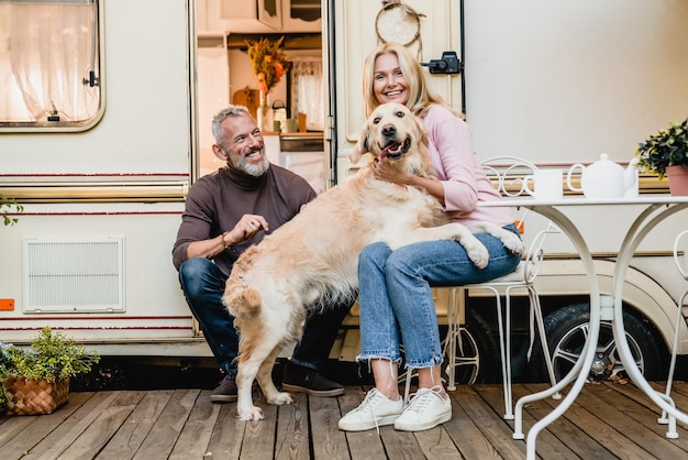 Photo family photo of mature caucasian couple playing with their retriever in the caravan doorway