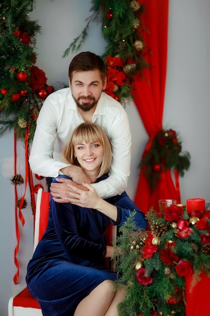 Foto di famiglia in uno scenario rosso brillante un uomo vestito con una camicia bianca e una donna con un bel vestito.