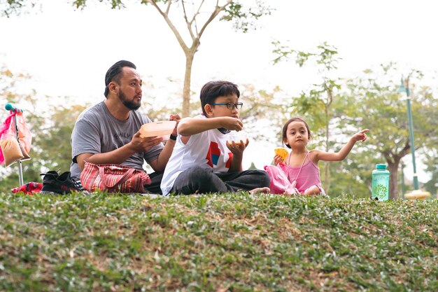 Photo family picnic and eating at the park