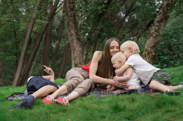 Family picnic at gaden park outdoors Mom and three children rest on picnic blanket