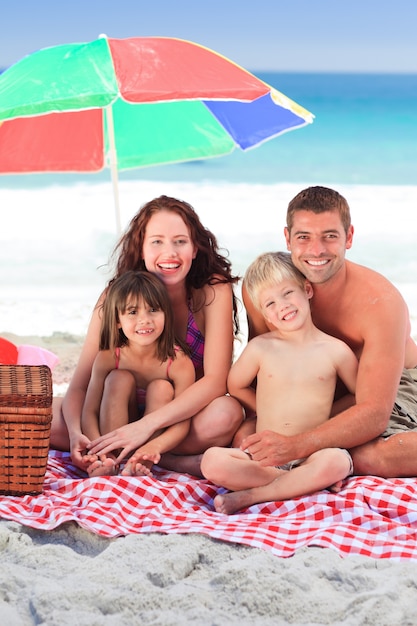 Foto famiglia che fa un picnic sotto un ombrellone sulla spiaggia