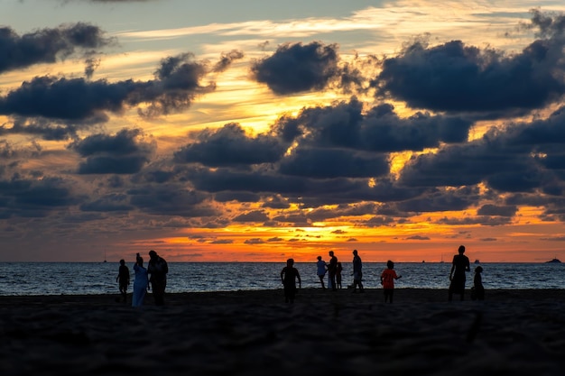 夕日と美しい夕日のビーチで遊ぶ家族