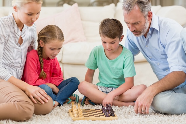 Family playing chess together at home in the living room