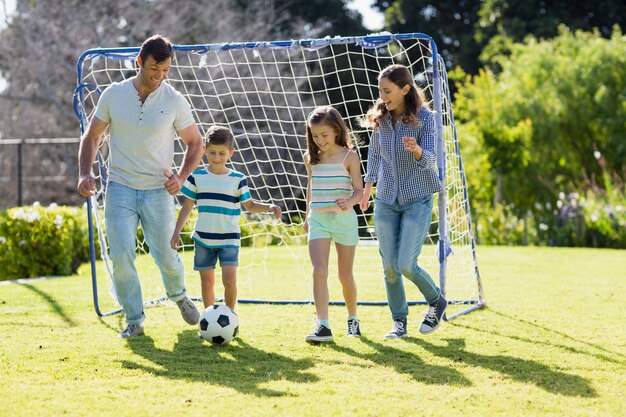 家族が公園でサッカーを一緒に遊んで