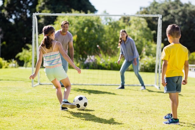 家族が公園でサッカーを一緒に遊んで