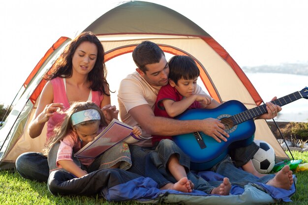 Famiglia che suona una chitarra in una tenda