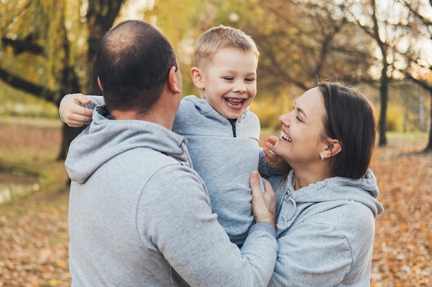 Foto famiglia che gioca con un bambino mentre si gode il parco autunnale ritratto del primo piano sorridente bambino felice genitore figlio famiglia felice all'aperto madre natura