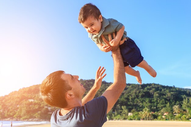 Family playing with the son on the beach at the sunset time