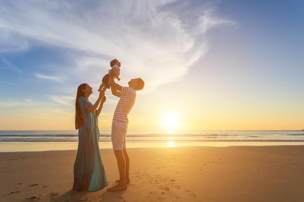 Family playing with the son on the beach at the sunset time