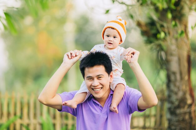 庭で父親と幸せに感じる6ヶ月の赤ちゃんの家族の肖像