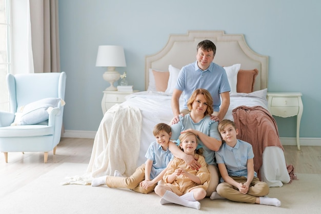 Family portrait caucasian parents with children are sitting on floor in bedroom an attractive large ...