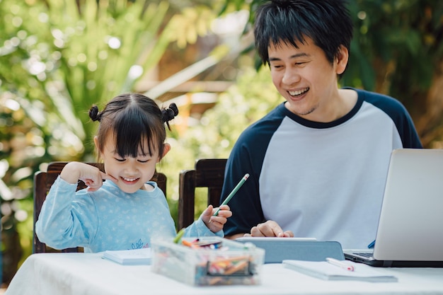 Family portrait of father and preschool daughter use computer for study at home