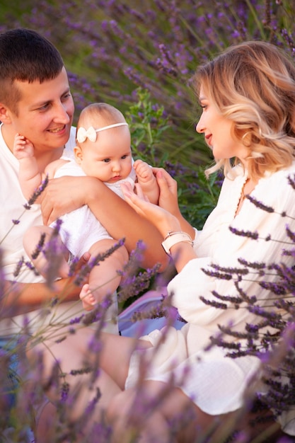 Family portrait mother father and baby on lavender field having fun together. Happy couple with chil