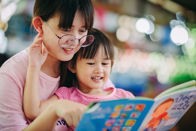 Family portrait of mother and kids reading a book together.