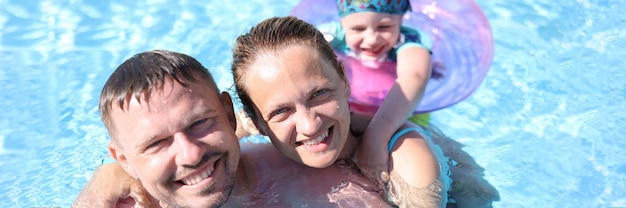 Family portrait of smiling parents and child in pool