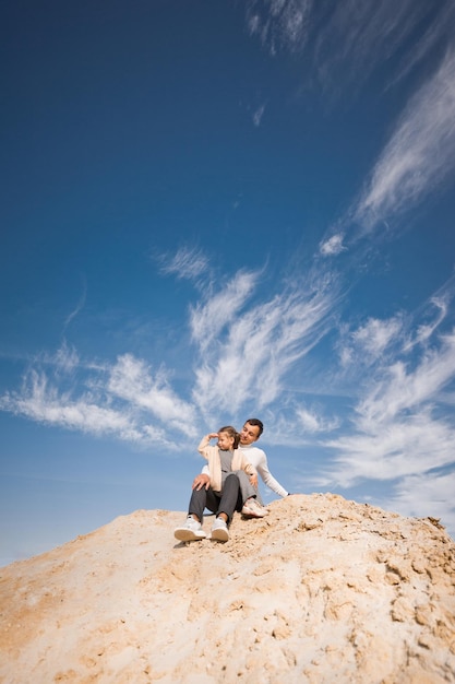 A family poses standing on a mountain of sand against the sky 3314