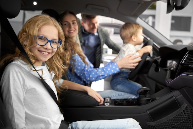 Family posing in car cabin of new automobile.