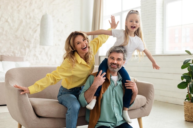 Family posing having fun daughter sitting on fathers shoulders indoor