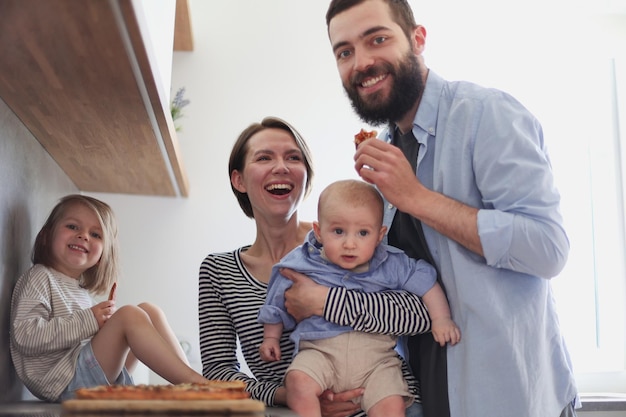 Family of  posing in the kitchen smiling and happy