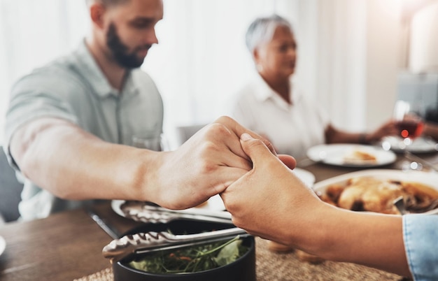 Family prayer holding hands zoom and dinner buffet at home of grandparents with father at a table Worship praying and food for a holiday together in a house with spiritual gratitude for feast