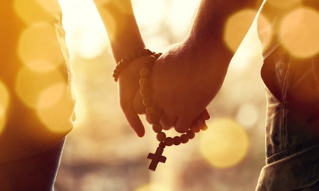 Family praying, closeup man and woman holding hands and prayer rope