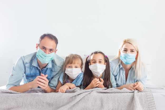 Family on quarantine, home isolation while coronavirus, husband, wife and a kids in the bed, family in face masks