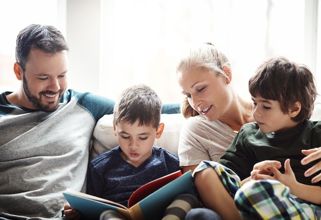 Family reading book together with parents and kids happiness at home with story time and learning Love relationship and happy people bonding in living room education and mom dad with children